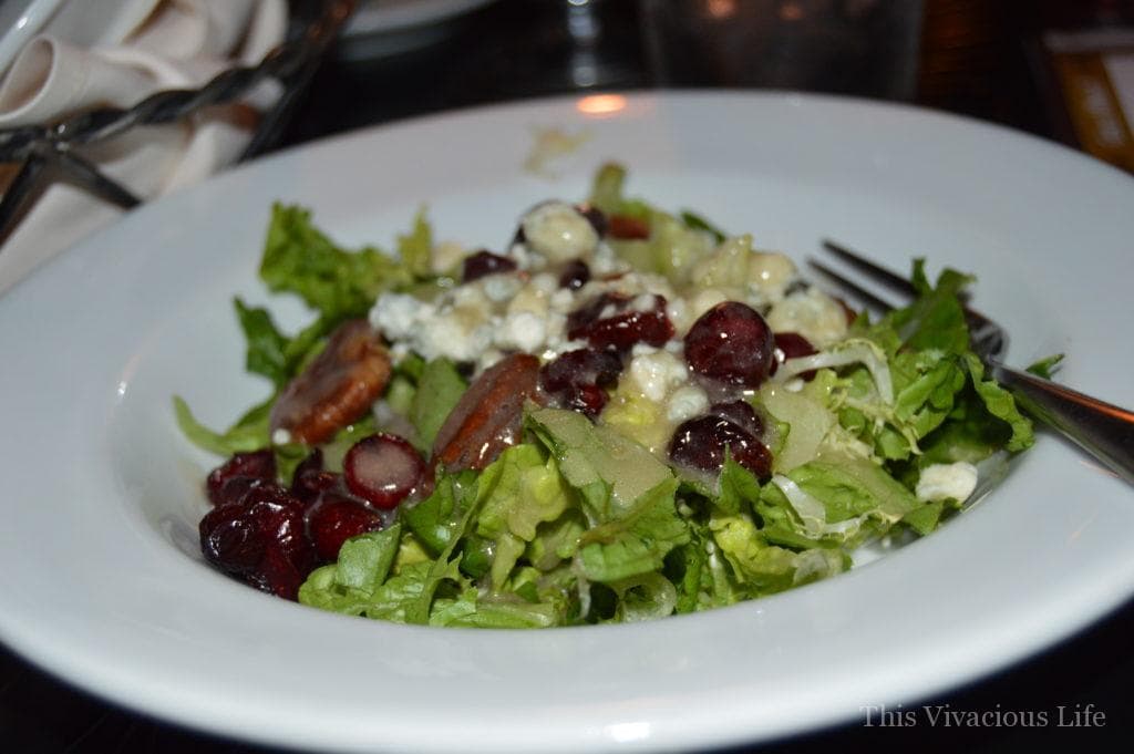 Green salad with pecans and cranberries in a white bowl
