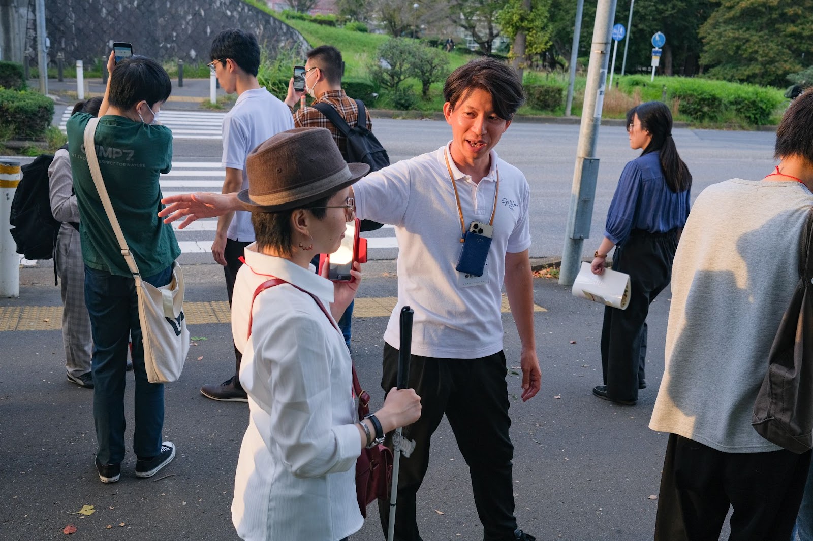 屋外の横断報道の前で「EyeNavi」を体験する参加者たち。