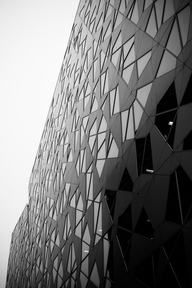 A black and white photograph of a building with a glass facade designed using parametric design principles