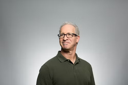 A man posing slightly tilted at a comfortable angle for a professional headshot