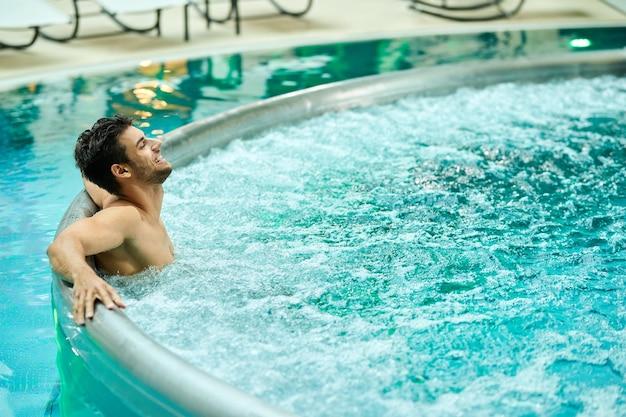 Free photo young relaxed man enjoying in a hot tub while spending a day at wellness center
