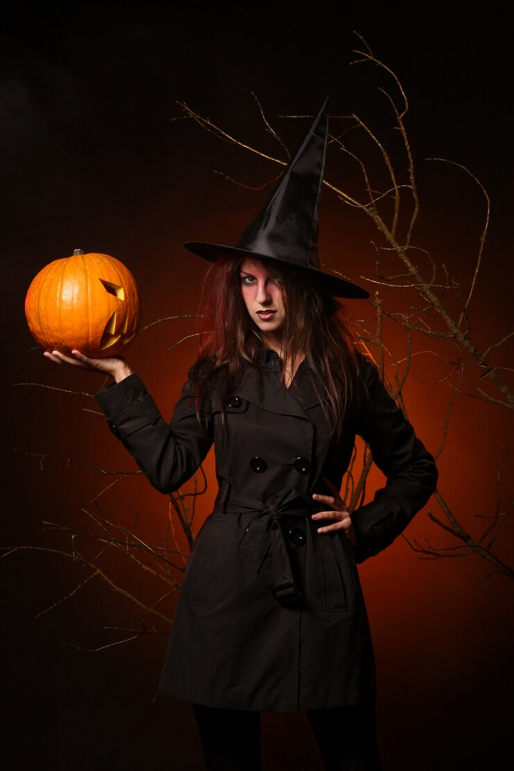 A women dressed as a witch and holding a pumpkin for Halloween.