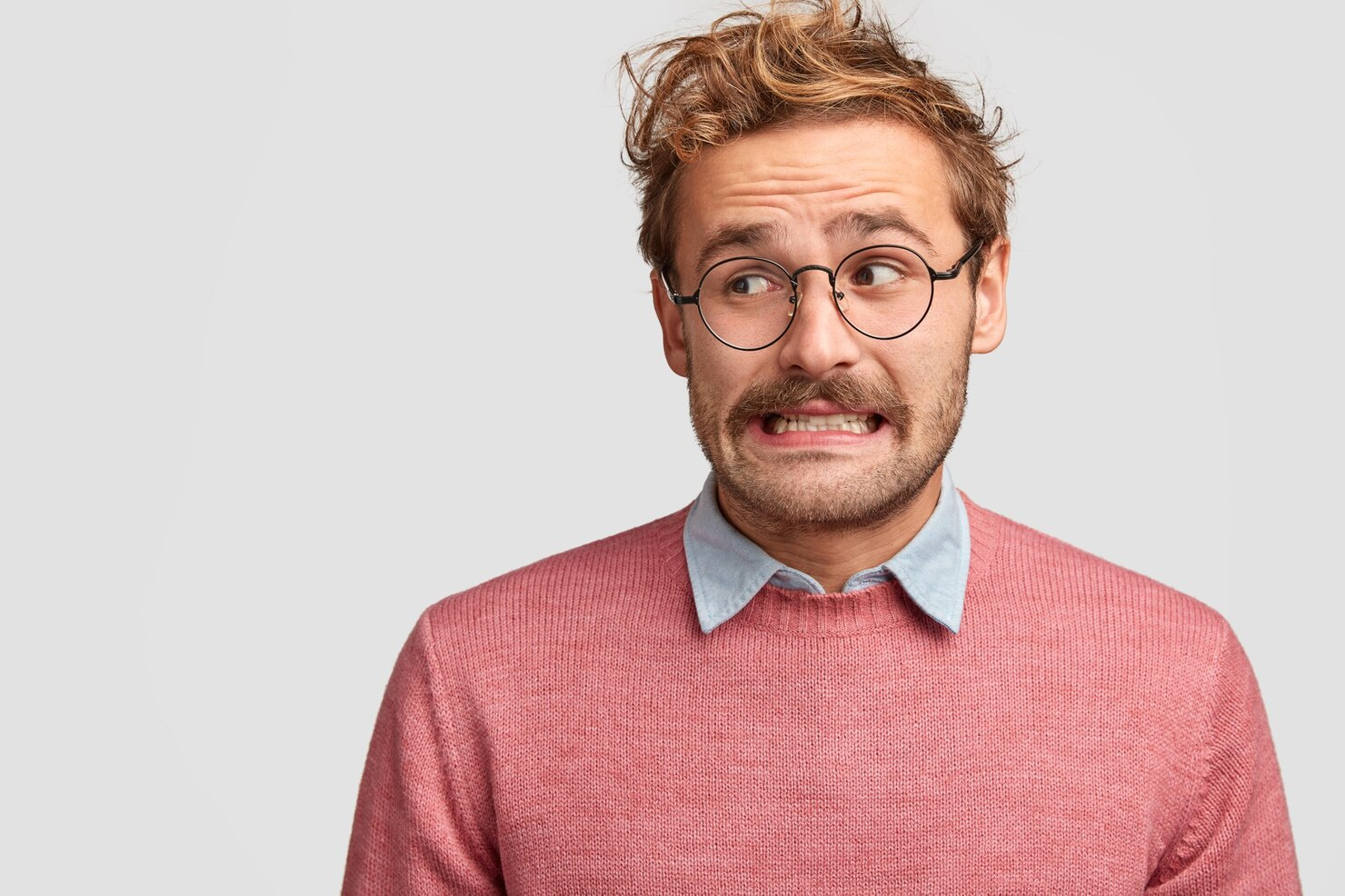 A man in glasses looks away while making silly expressions.