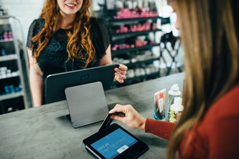 A woman confidently uses a digital device for payment, leveraging the best customer reference management software for 2024.
