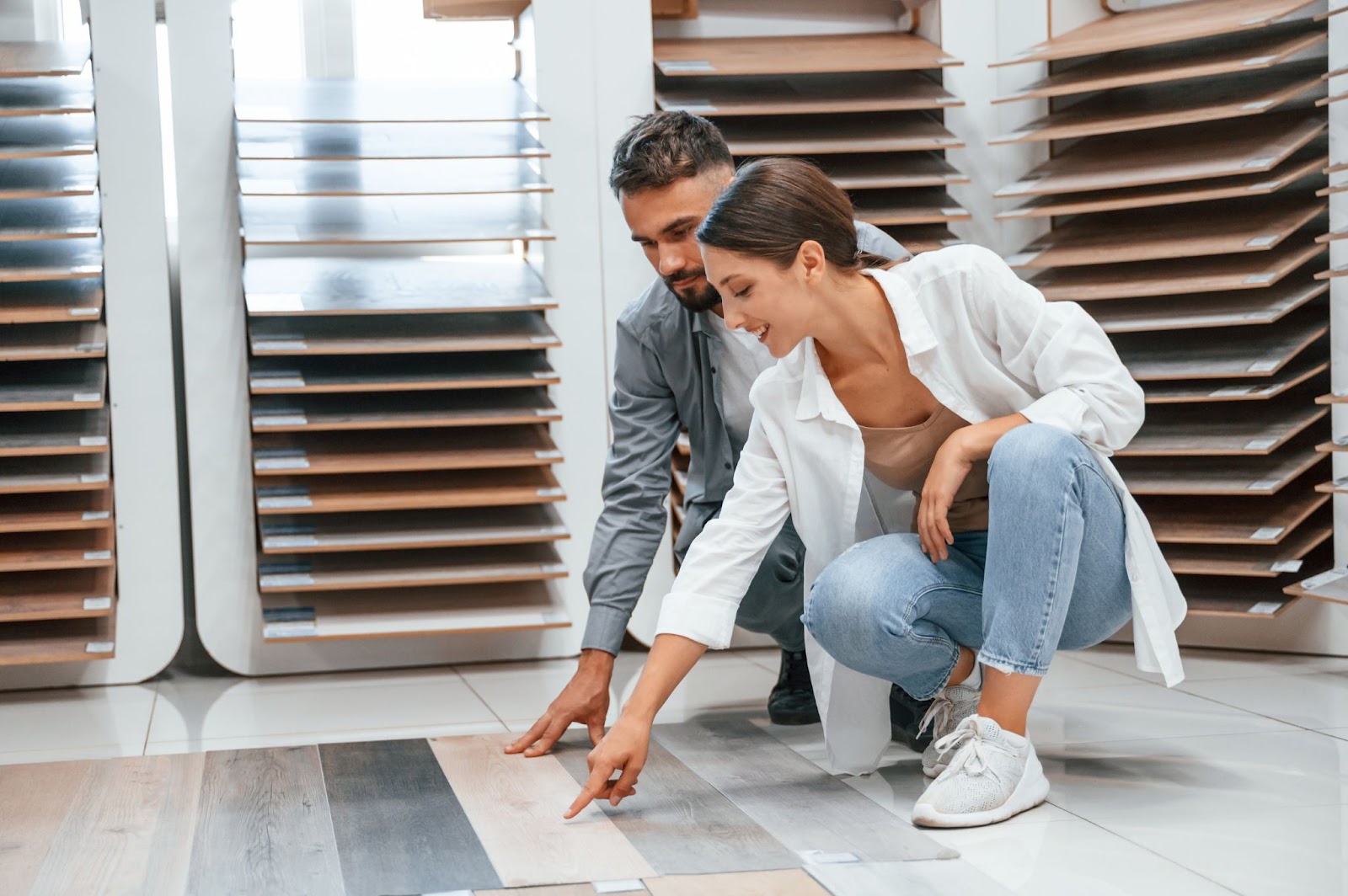 A couple kneeling down to inspect different types of flooring designs.