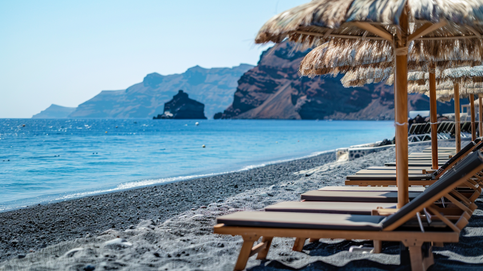 Sun loungers lined up along the beach in Santorini