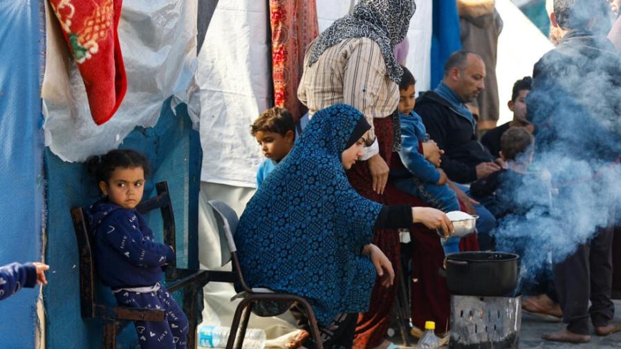 A woman cooks as Palestinians, who fled their houses amid Israeli strikes, shelter at a United Nations-run school, amid the ongoing conflict between Israel and the Palestinian Islamist group Hamas, in