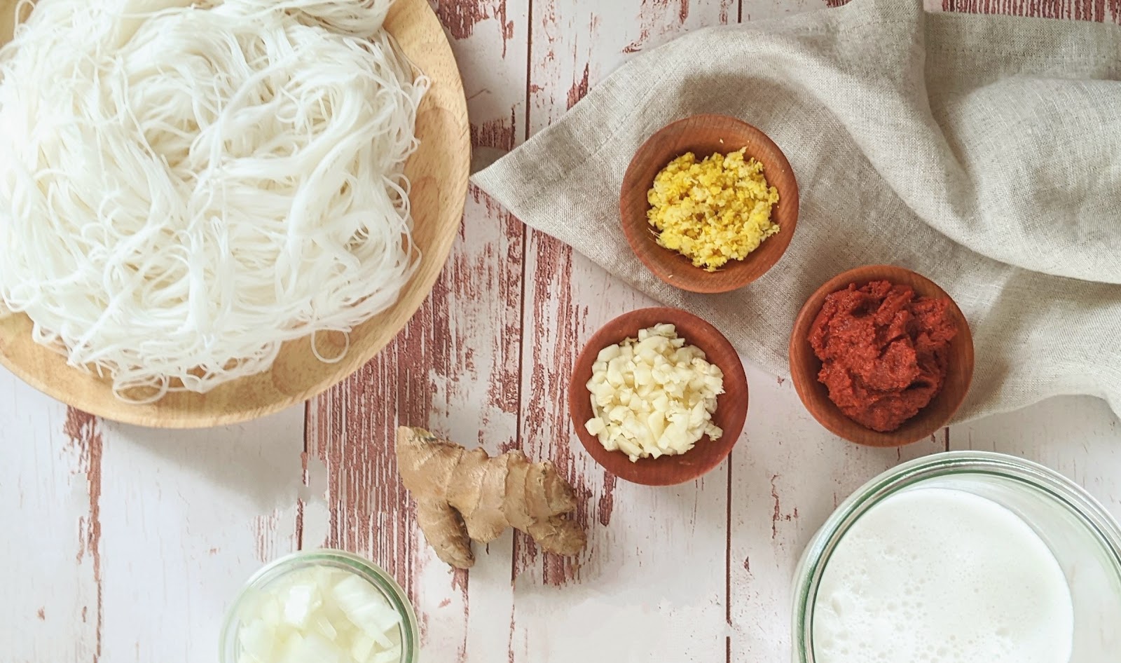 top down view of ingredients needed to make Thai chicken noodle soup including chicken, noodles, curry paste, ginger, garlic