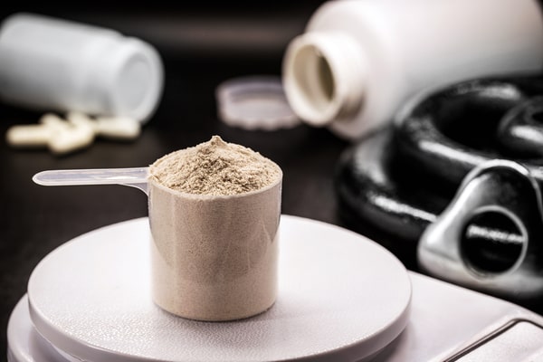 A measuring spoon of protein powder placed on a weighing scale