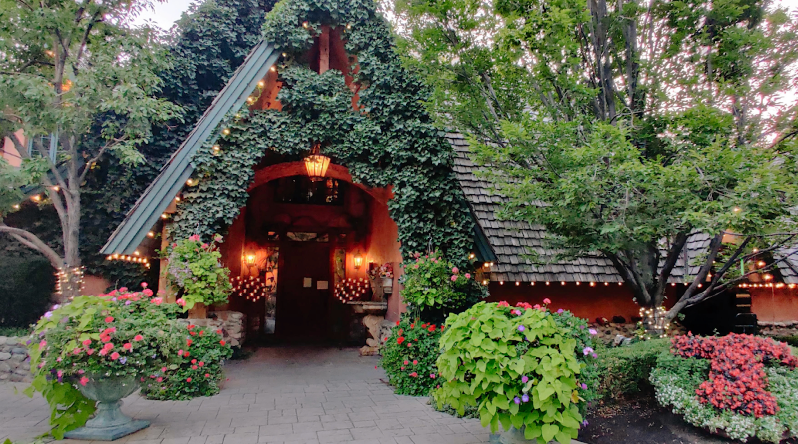 The entrance to Tuscany, a restaurant covered in blooming flowers and foliage. 