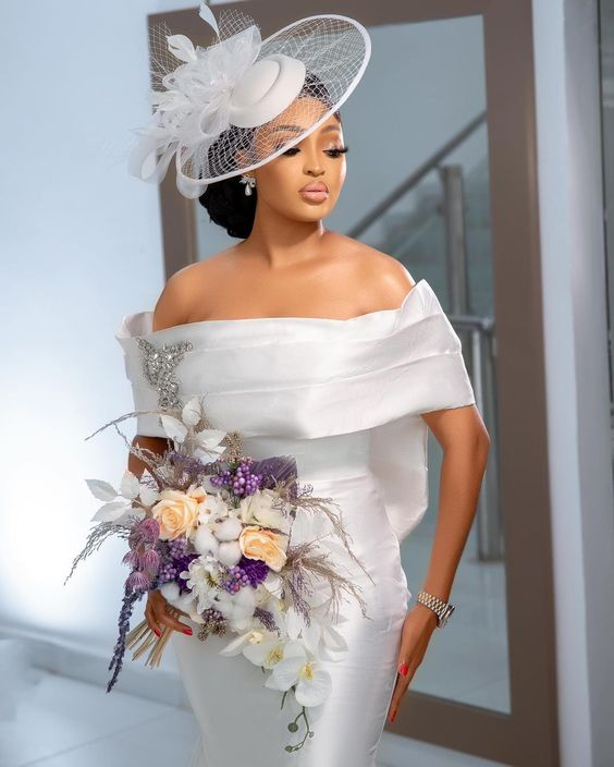 Picture of a lady in a civil wedding gown pairs her look with a  nice fascinator hat to match
