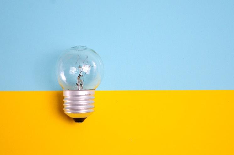 A light bulb on a yellow and blue background

Description automatically generated