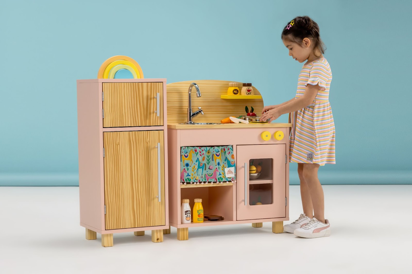 Criança brincando com a mini cozinha de brinquedo da Ateliê Materno.
