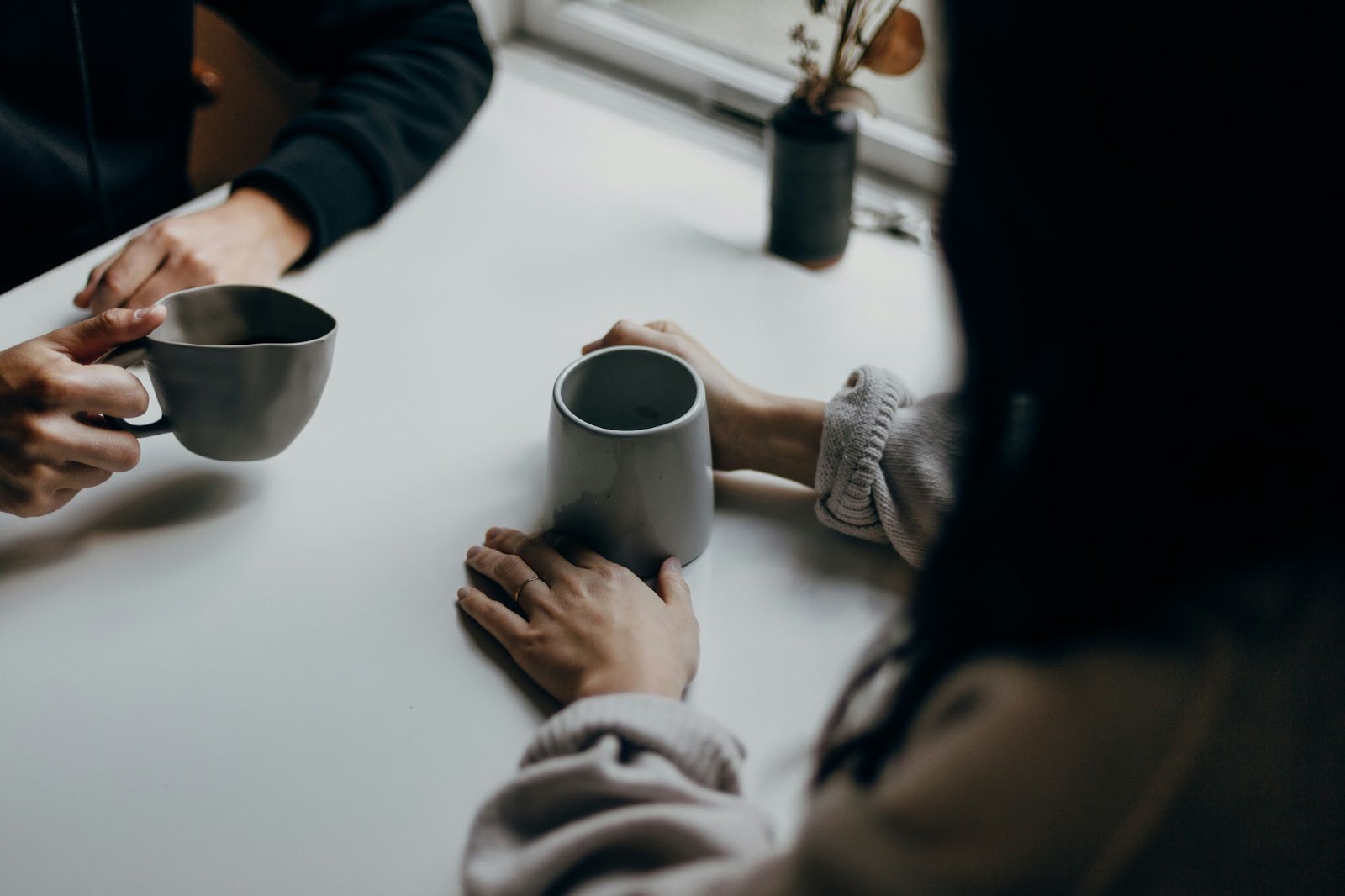 Two people sat at a table, each holding their own coffee cup.