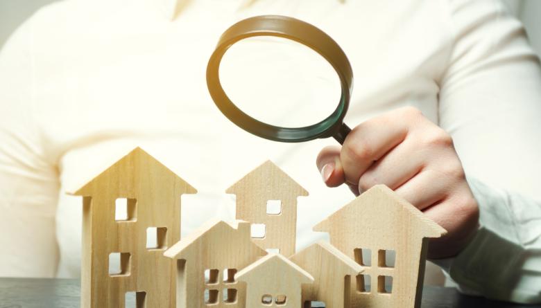 person looking at houses through magnifying glass