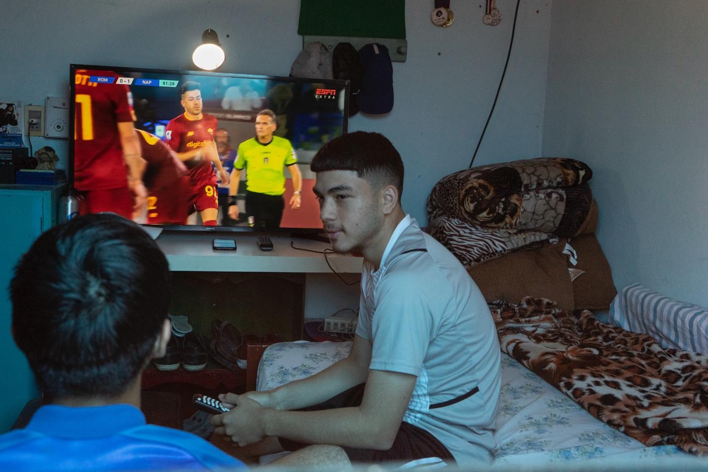 Thobías con su amigo Esteban sentados en la sala jugando a la Play Station