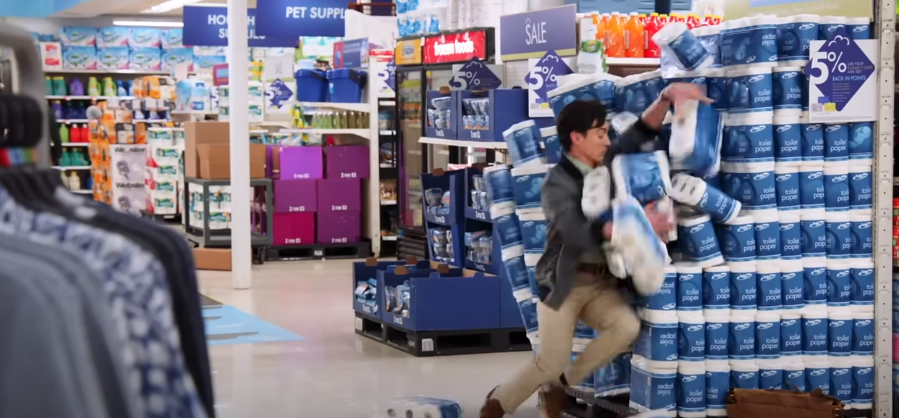 a man tripping into a stack of toilet paper