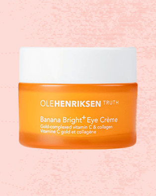 Ole Henriksen Banana Bright Eye Crème against a pale red background.