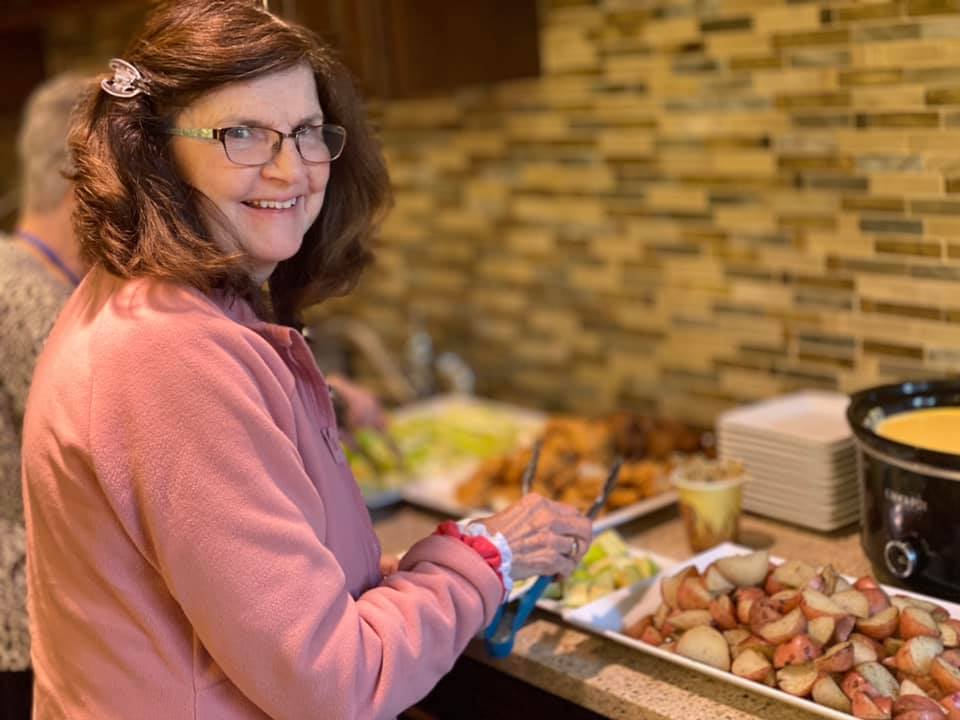 A woman picking food from a buffet