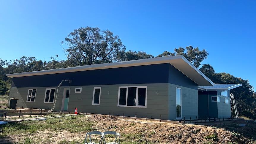 A home under construction with slanted roof panels, and light paint colours on a sunny day.