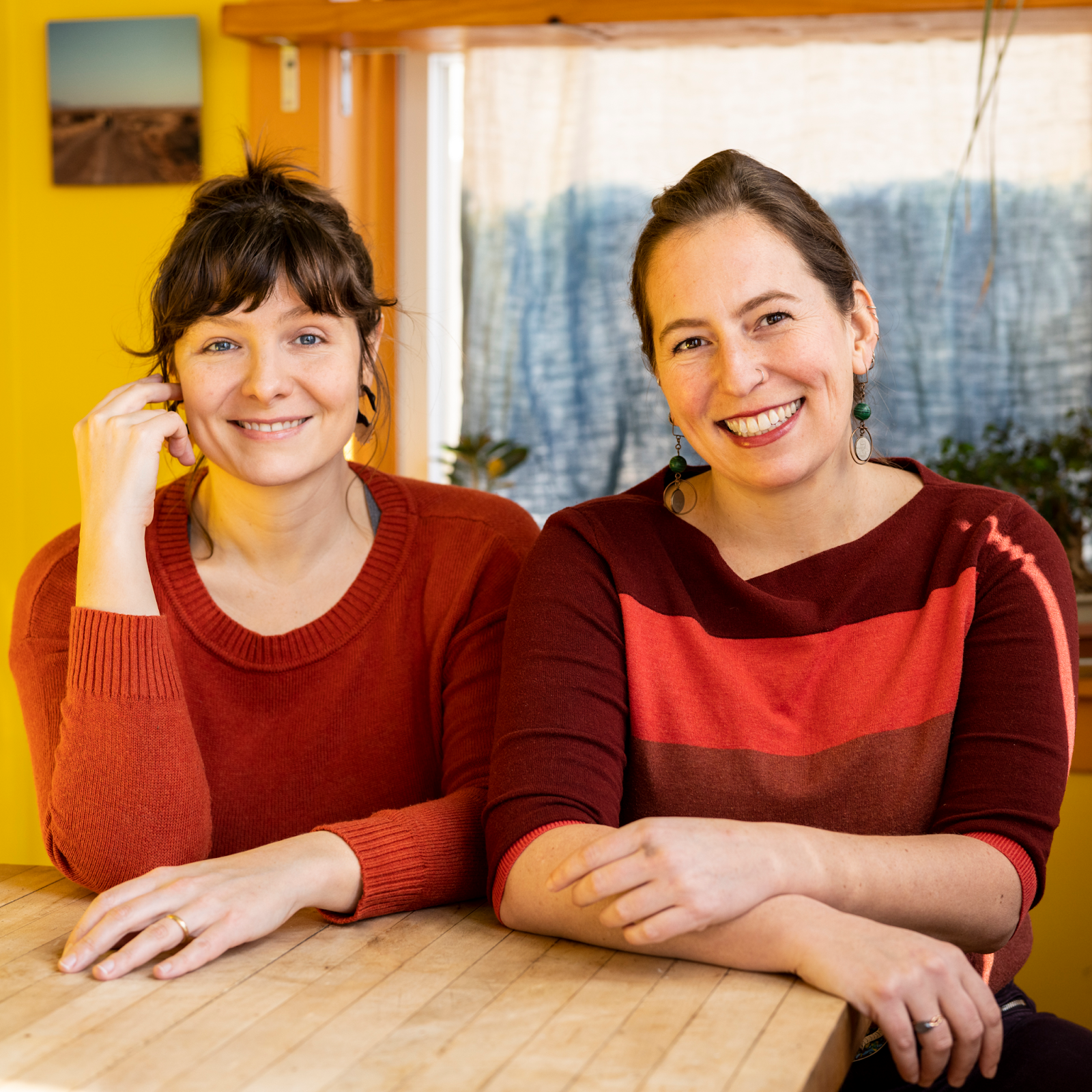 A photo of two women sitting at a table and smiling.