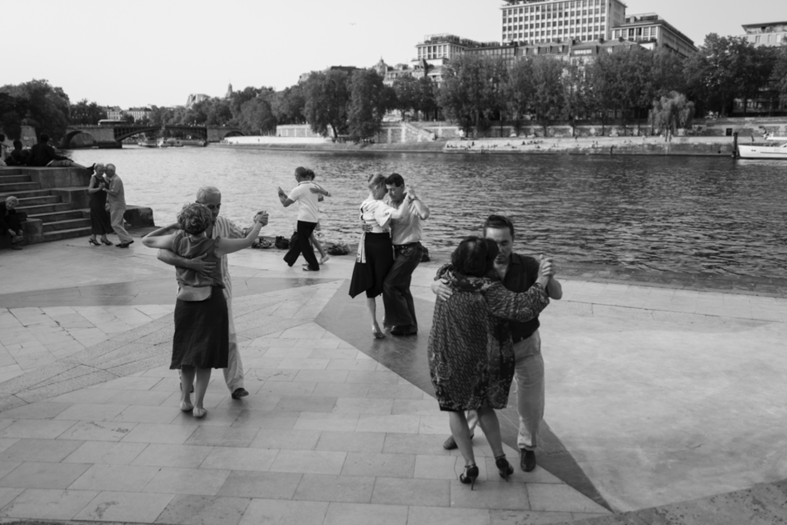 A black and white image of people dancing outside in front of a river.