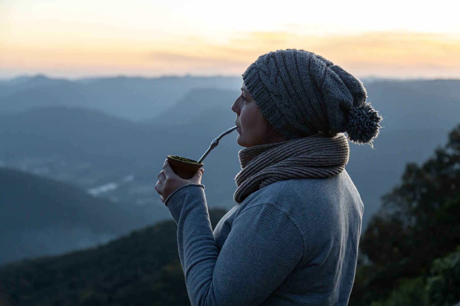 Mulher com touca e cachecol tomando chimarrão na Serra Gaúcha.