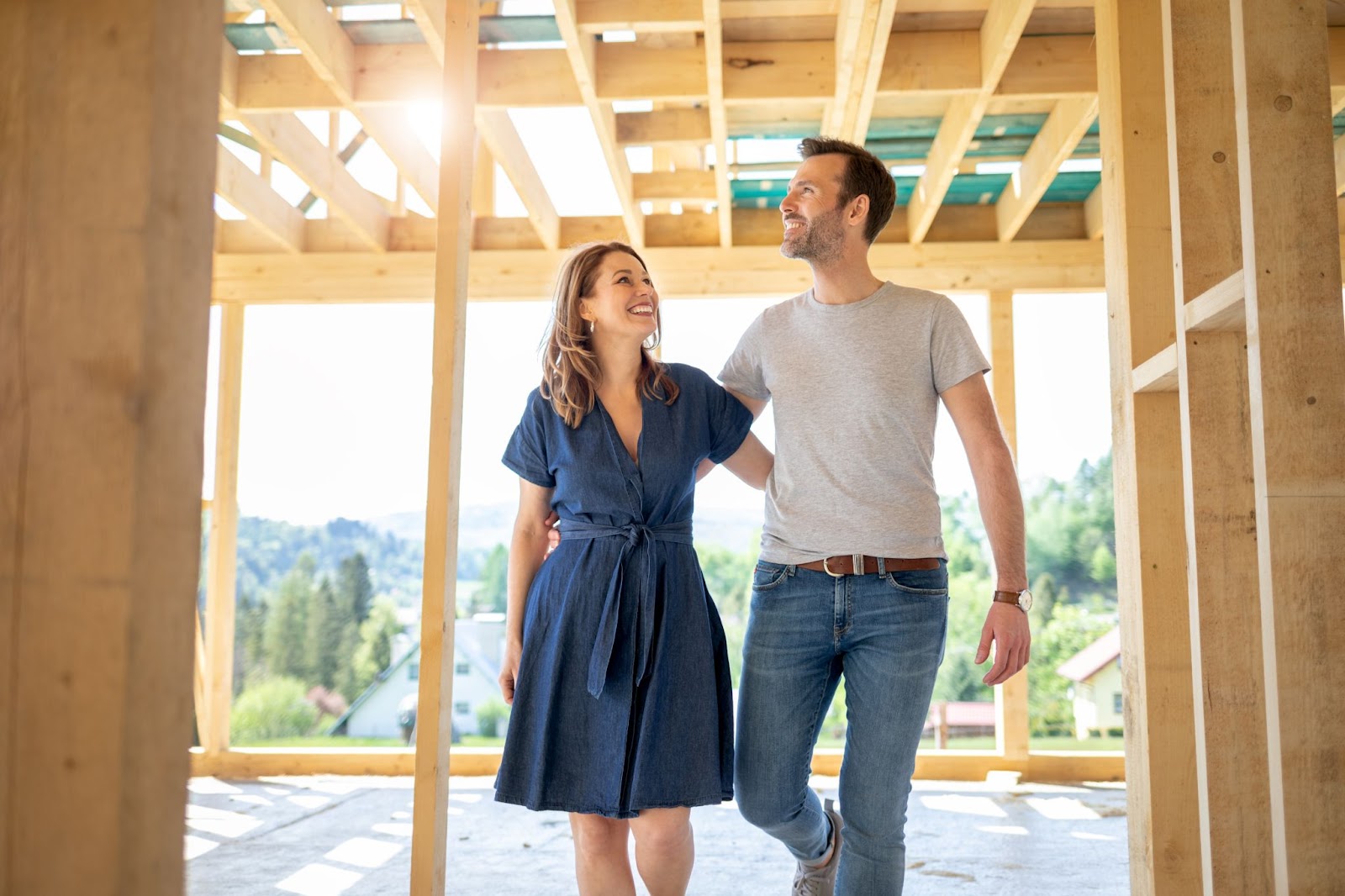 A couple exploring a house under construction, examining the unfinished rooms and envisioning their future home.