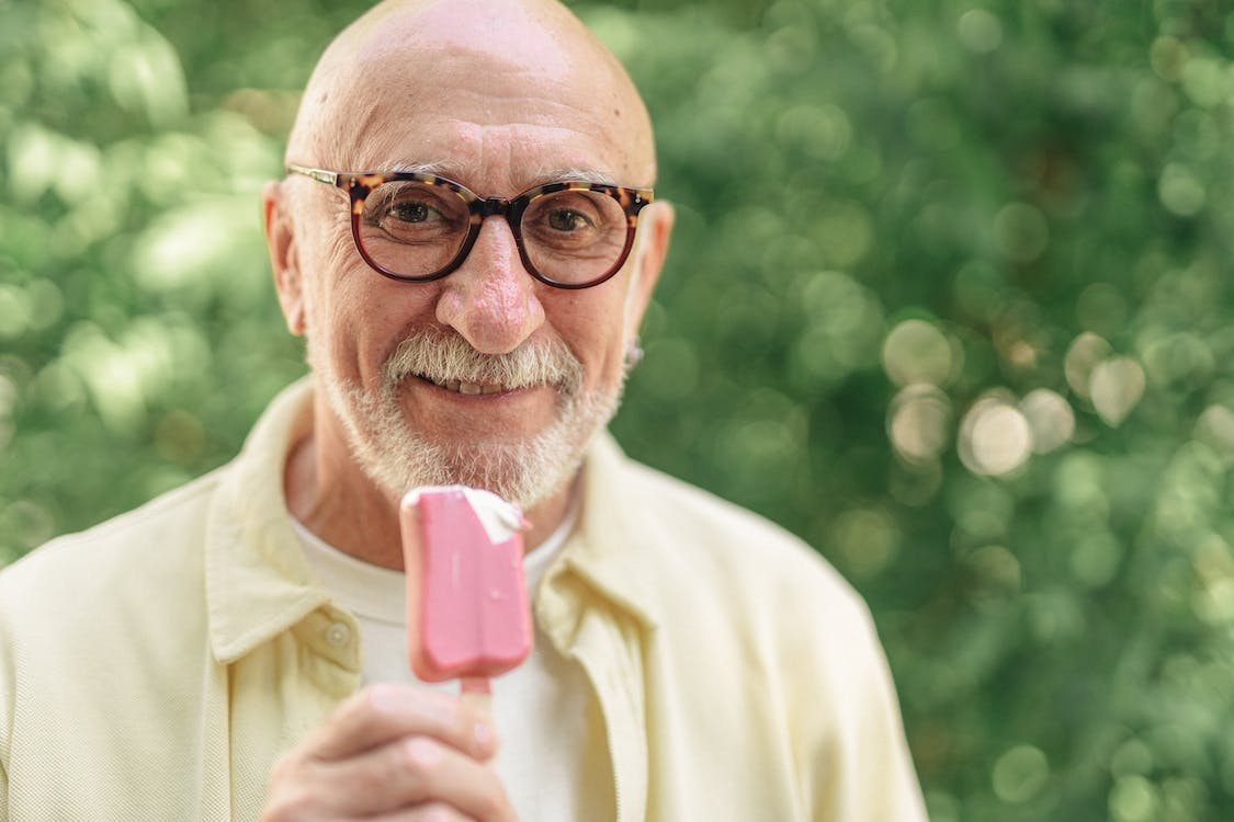 an elderly man holding a pink ice cream