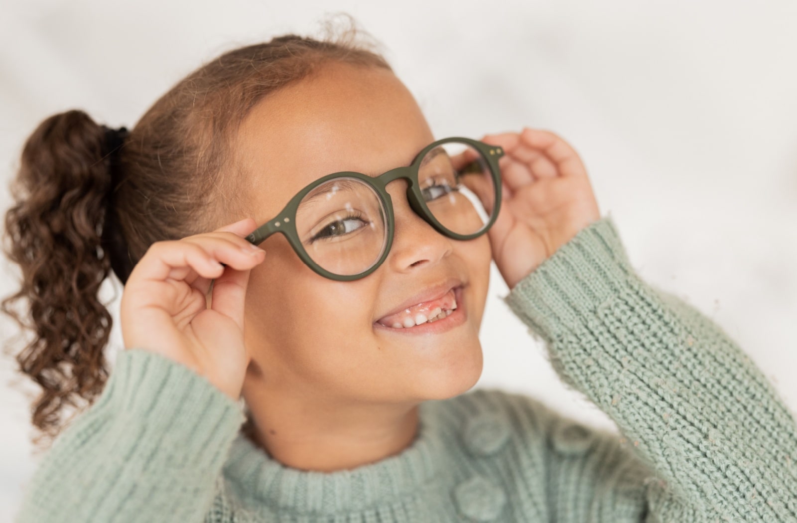 A young girl smiling and wearing corrective lens glasses