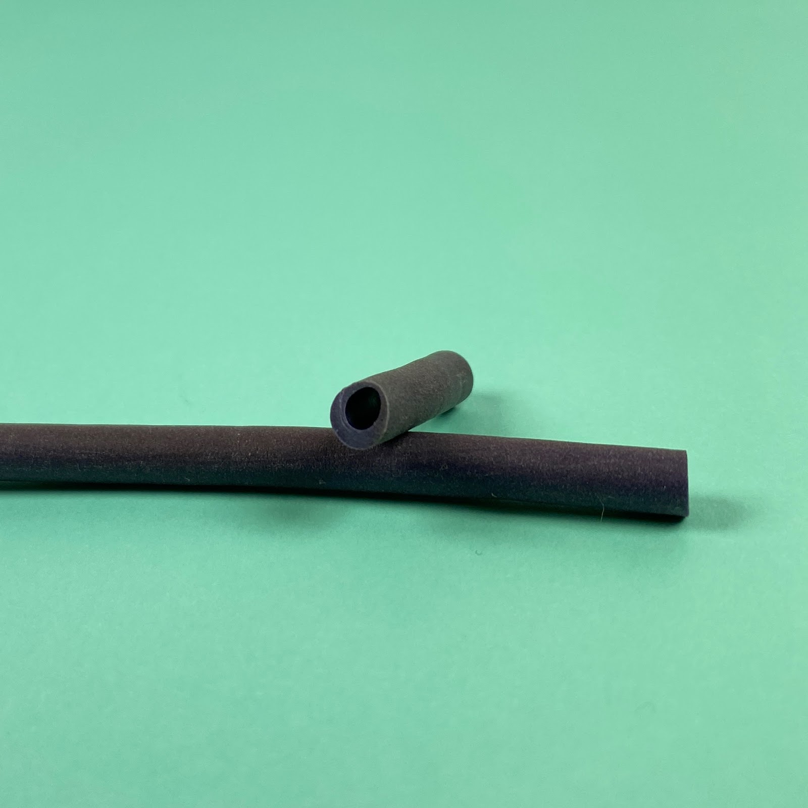 Photo showing the hollow tube of polymer clay along with a long skinny bead cut from it