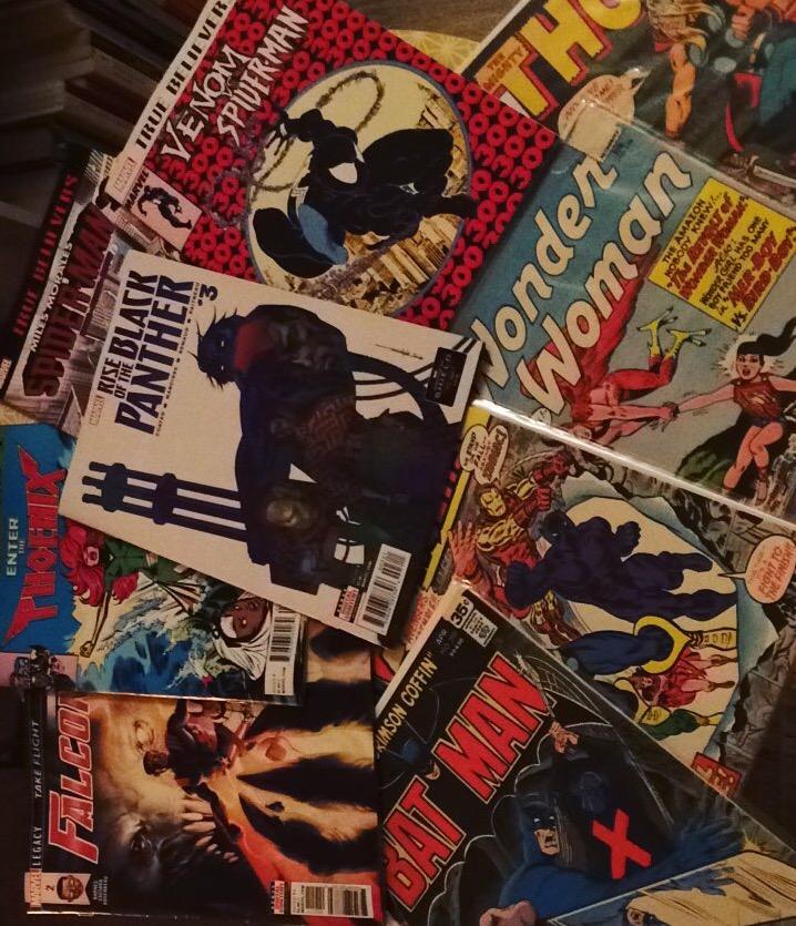 Image of a stack of comic books, including Black Panther, Bat Man, Wonder Woman, Venom and more. 