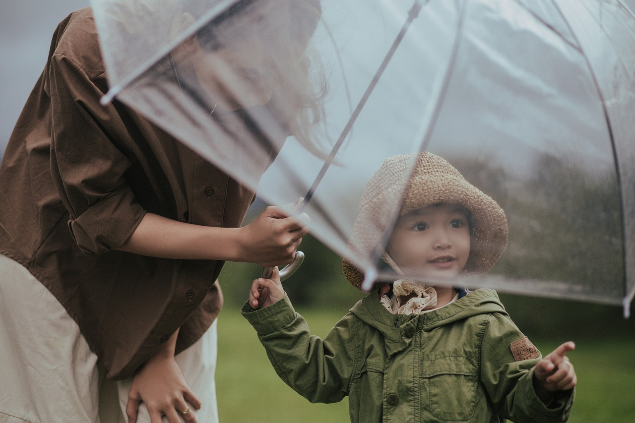 mother and daughter hold an umbrella in the rain
