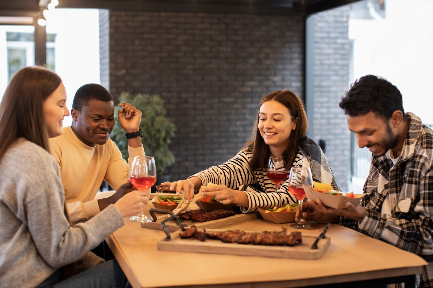 Four friends sharing joy at a Friendsgiving feast.