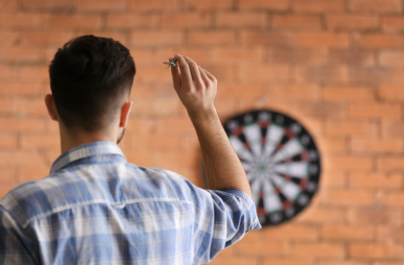 A man playing darts, a sport that requires good hand-eye coordination.