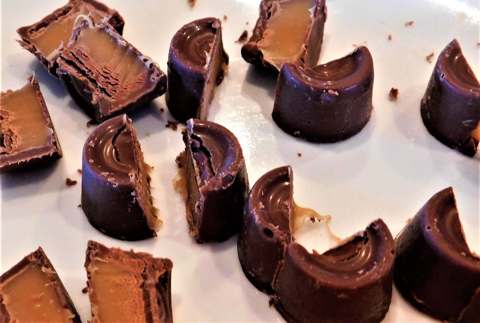 Chocolate caramel candies broken in half to reveal the gooey, rich caramel filling inside, showcasing their luscious texture and inviting sweetness.