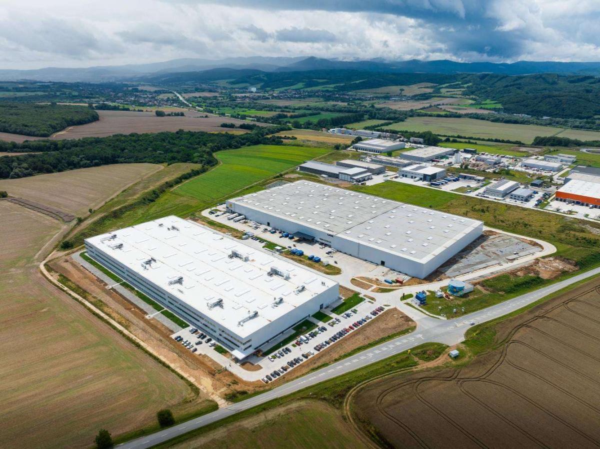A large white building surrounded by fields
Description automatically generated