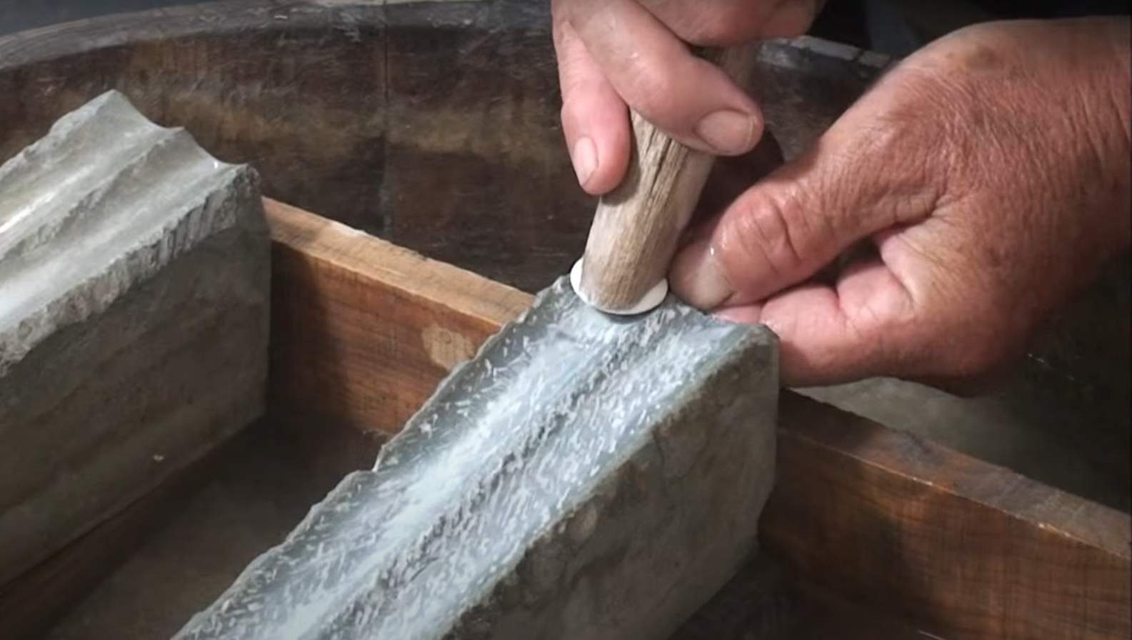 A person using a hammer to grind a stone

Description automatically generated