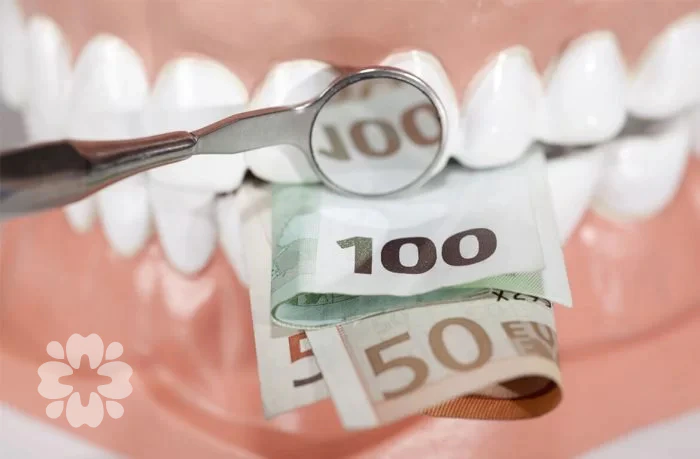Một chiếc gương nha khoa phản chiếu tờ 100 euro được đặt trên một bộ răng mô hình
