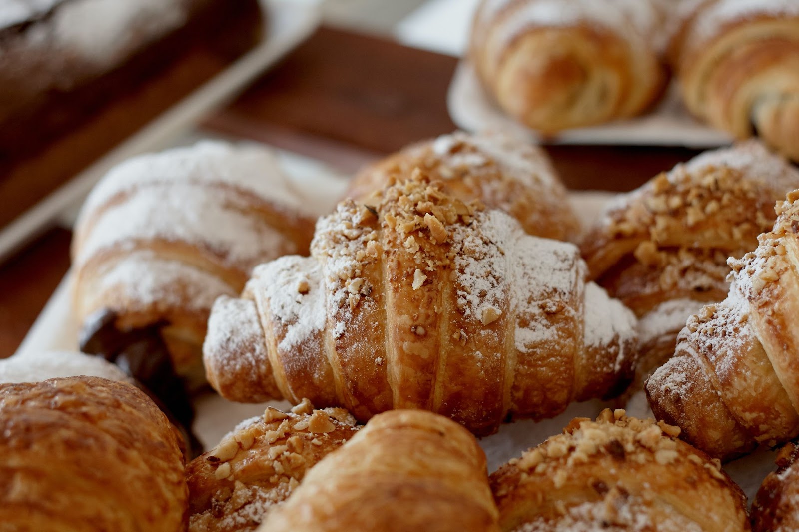 Croissants sprinkled with nuts and icing sugar on a baking sheet