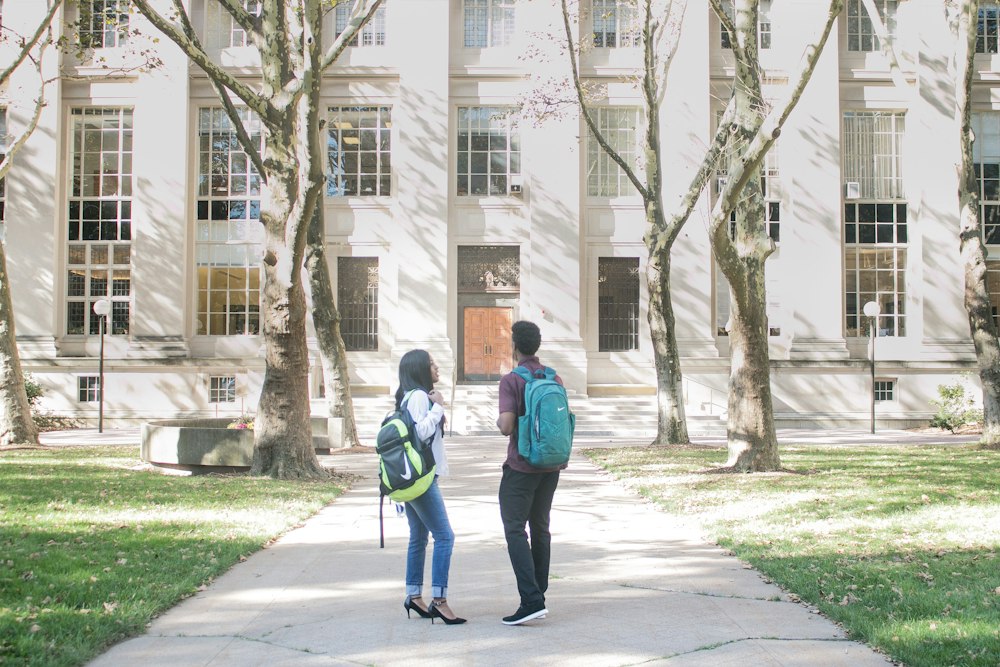 Two students standing in front of an academic building - Making The Most of College Orientation