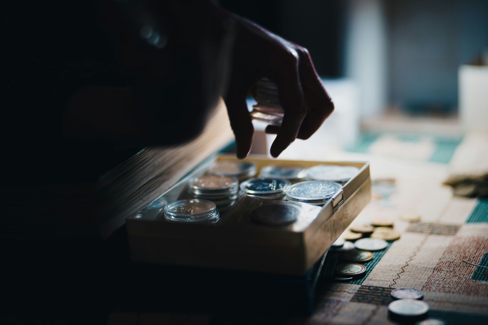 a hand placing some coins into a wooden box