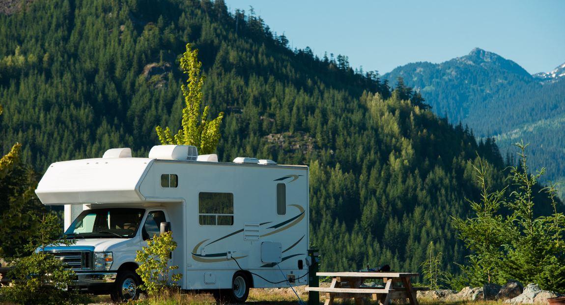 A white camper parked in front of a mountain

Description automatically generated