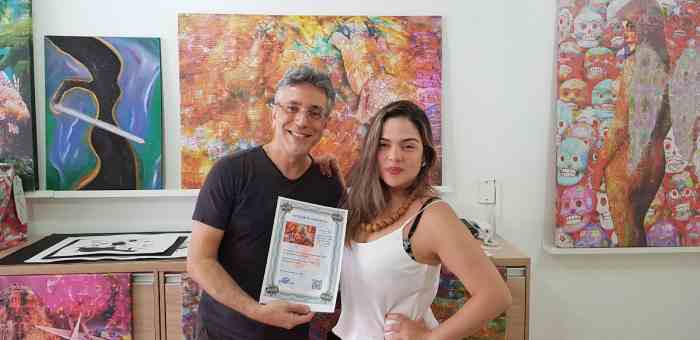 O artista Henrique Vieira Filho e a cantora Erica Pinna recebendo a obra “Wall Music”
