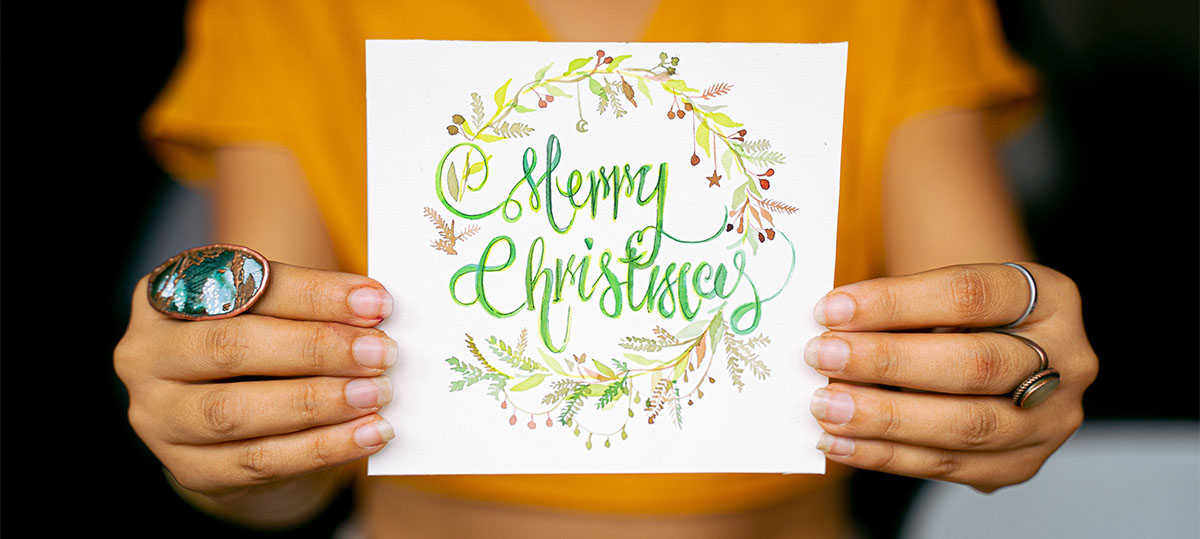 Mulher segura cartão com mensagem de feliz Natal em inglês