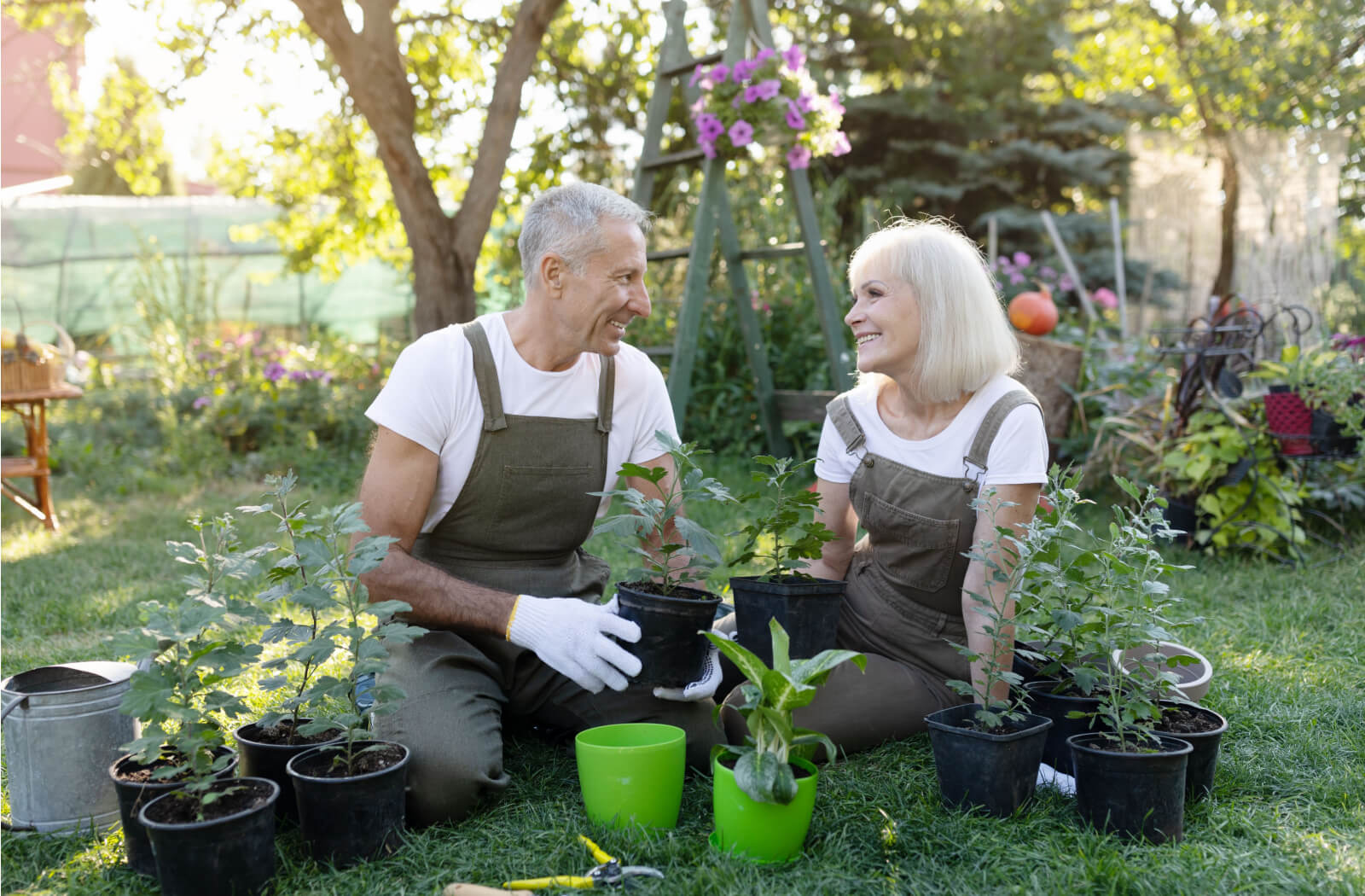 A senior man and a senior woman smiling while gardening outside.