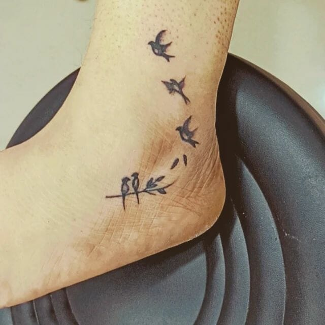 Birds taking flight in black ink on ankle