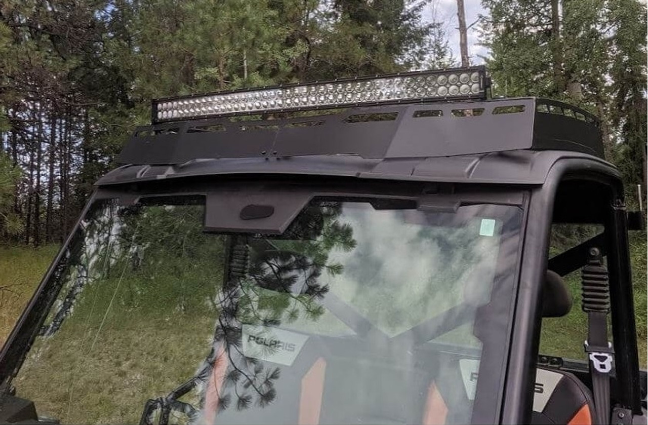 A Polaris Ranger XP1000 light-bar-compatible roof rack, installed on a parked UTV with a grassy field and trees in the background.