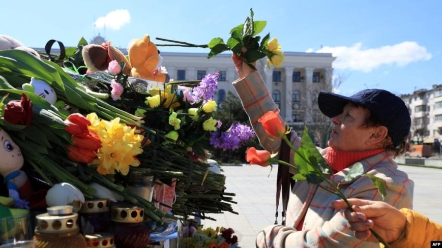 Một người phụ nữ đặt hoa tại nơi tưởng niệm nạn nhân vụ xả súng ở Simferopol, Crimea, hôm 24/3.