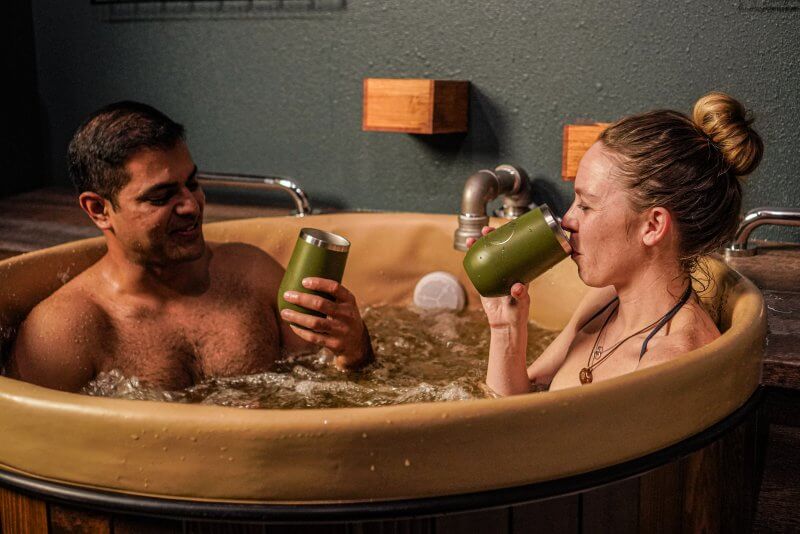 couple taking a beer bath and drinking from tumblers at Oakwell Beer Spa